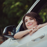 A woman looking outside the window of a car with a smile on her face. "Happy to be starting a new journey"